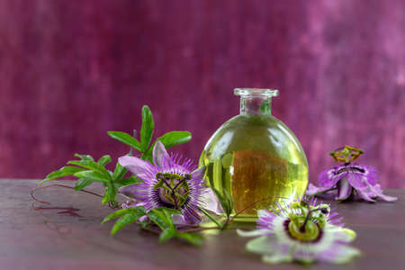 Bottle of vegetable oil surrounded by passionflowers on a magenta background