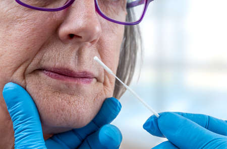 Screening virus-lab worker taking a mucus sample from female patient nose