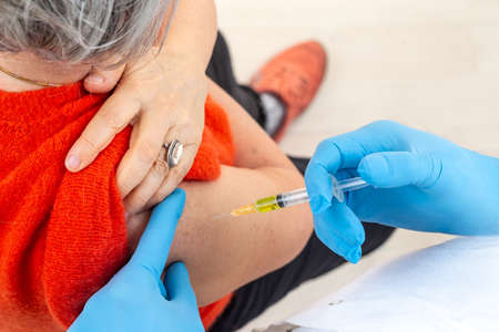Vaccination of seniors protection -medical mask. Covid-19 or coronavirus vaccine-Doctor holding syringeの写真素材