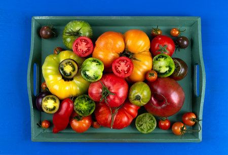 Old tomatoes whole and sliced in half in a green tray.の写真素材