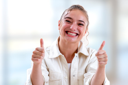 Young woman bursting out laughing on a light and blurry backgroundの写真素材
