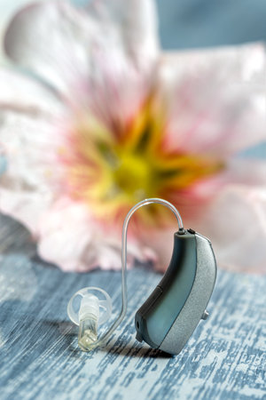 Close-up auditory rothesis with a flower in the background symbolizing the ear.
