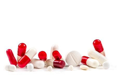 Red and white capsules and tablets and medicines close-up on a cropped white background.の写真素材
