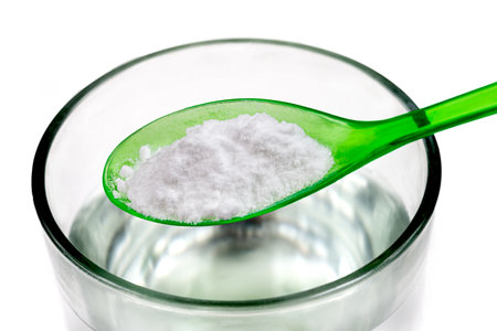 Spoon of baking soda over glass of water, isolated on white backgrpndの写真素材