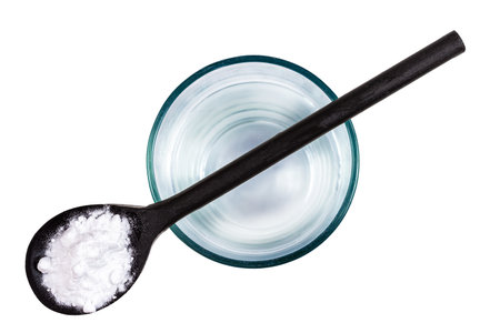 Spoon of baking soda over glass of water, isolated on white backgrpndの写真素材