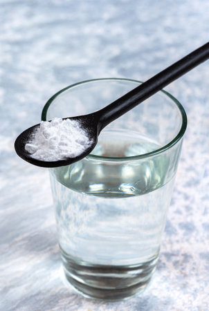 Spoon of baking soda over glass of water, isolated on white backgrpndの写真素材