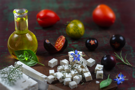 Bottle of olive oil and tomatoes with leaves feta cheese and basil isolated on a brown backgroundの写真素材