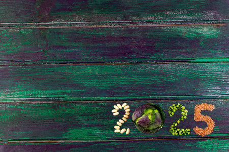 Happy New Year 2025 number made of fruits and vegetable on green wooden plankの写真素材