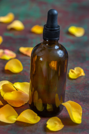 Romantic aromatherapy. petals, rose essential oil in dark glass bottle. wooen backgroundの写真素材