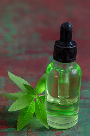 A bottle of common vervain essential oil with fresh blooming verbena officinalis plant wooden backgroundの写真素材