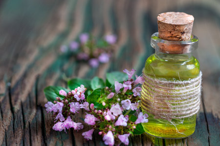 Essential oil of oregano in a bottle and fresh flowers on a wooden table Natural cosmetics and aromatherapyの写真素材