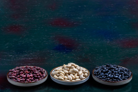 Assortment of beans , red,white, black in wooden spoon on dark wooden backgroundの写真素材