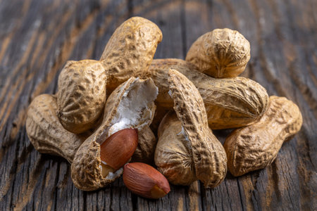 Peanuts in their shells arranged on a rustic wooden surface showcasing their natural texture and colorの写真素材