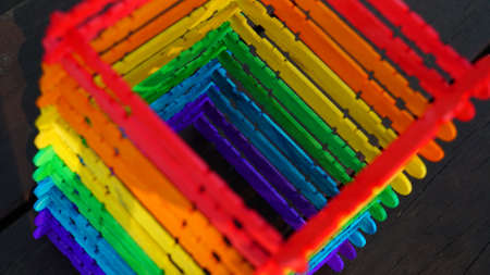 a tower made of rainbow-colored wooden sticks on the tableの写真素材
