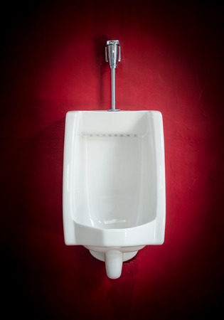White urinal on red wall with vignettの写真素材