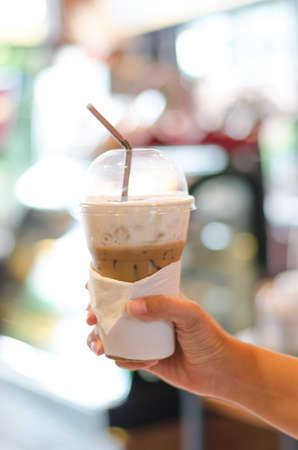 Cold coffee in plastic cup, blur coffee bar backgroundの写真素材