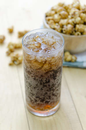 Cola with Ice and Popcorn on a wooden backgroundの写真素材