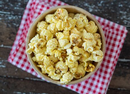 popcorn in brown bowl on dark wooden table.の写真素材