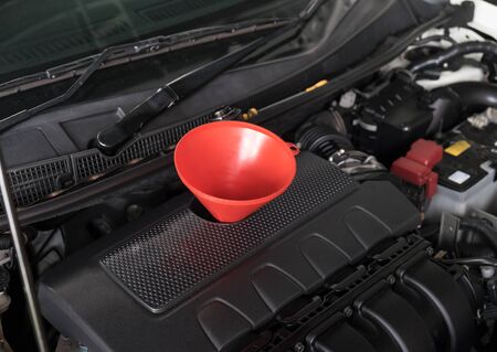 Car servicing mechanic pouring fresh oil to engineの写真素材