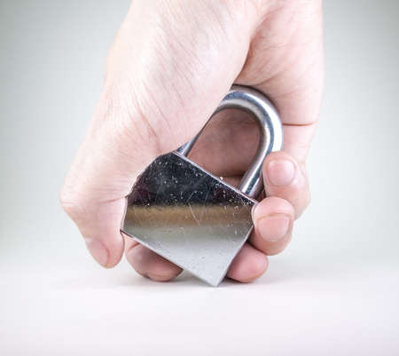 Hand holding the used, scratchy, silver padlock isolated on whiteの写真素材