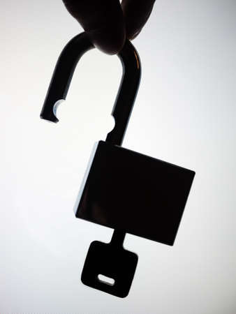 Silhouette hand picking up the unlock padlock. Abstract of security failure.の写真素材