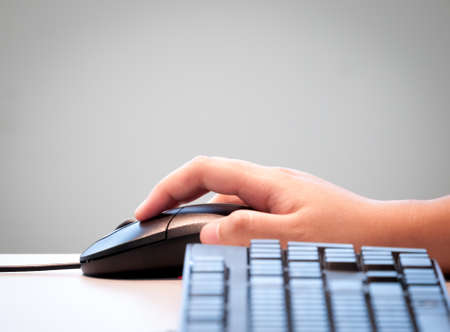 Hand holding black computer mouse together with keyboard in concept of computer user  Isolated on grey background for putting text on top の写真素材