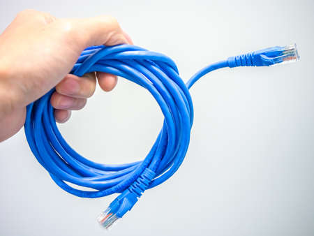 Hand holding LAN cable wire on bright backgroundの写真素材