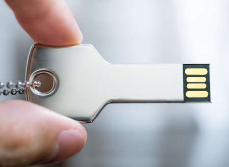 Macro image of a hand holding key-shaped USB drive in concept of technology securityの写真素材