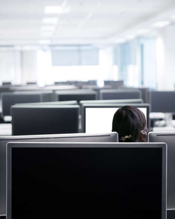 Woman employee working hard alone in the very early morning . Focus on the front monitor for putting some texts.の写真素材