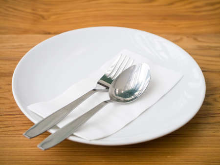 Empty plate with spoon and fork on wooden tableの写真素材