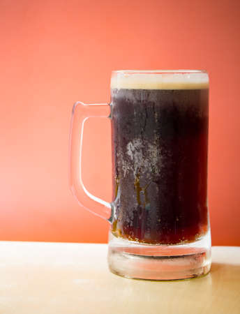 Cold root beer on top of wooden table in front of orange backgroundの写真素材