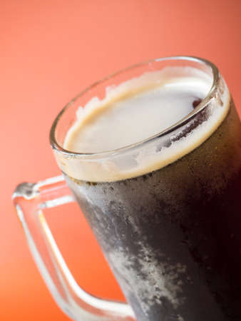 Closeup shot of root beer glass isolated on orange backgroundの写真素材
