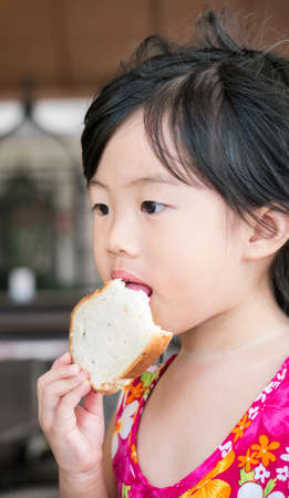 Portrait of the cute little girl eating breadの写真素材