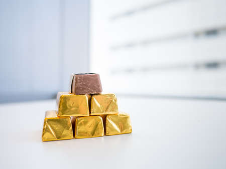 Chocolate candy in golden wrap on bright backgroundの写真素材