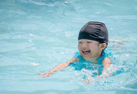 Happy asian kid smile while swimming in the poolの写真素材