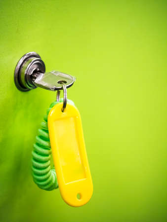 Yellow keychain hanging in the locker keyhole leaving space on right to put some text