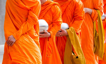 Buddhist monks holding silver buddhist alms bowl in hand walking together in the morningの写真素材