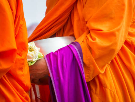 Buddhist monk holding alms bowl and lotus flower in religious conceptの写真素材