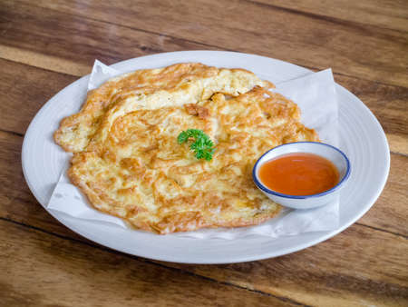 Omelette with chilli sauce served on wooden table topの写真素材