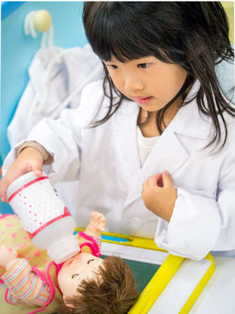 Adorable asian girl role playing doctor occupation wearing white gown uniformの写真素材