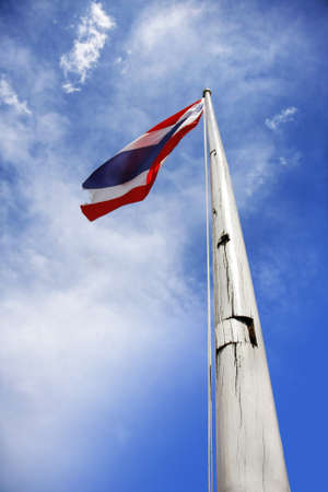 old flag of thailand holding up to beautiful blue sky with cloudの写真素材