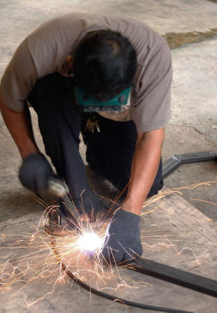 welder man welding steel on cement floor with spread spark and lighting around