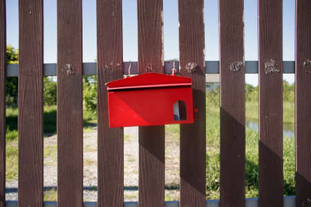 Red mailbox on brown gates front of houseの写真素材