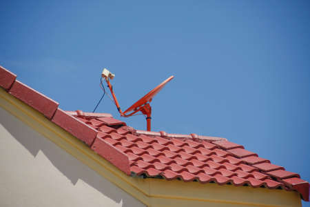red roof with a satellite dish and blue skyの写真素材