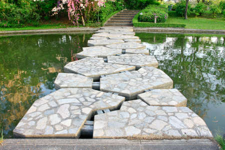 beautiful stone bridge cross pool with reflection green  tree on water