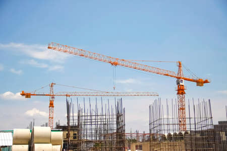 orange crane, building metal foundation pile and concrete pipe with blue sky on background