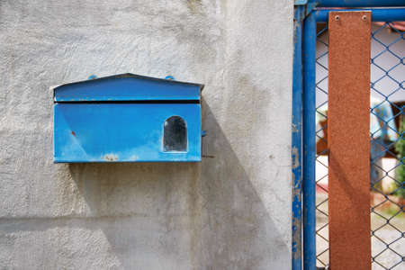 blue mailbox front of old cement wall of homeの写真素材