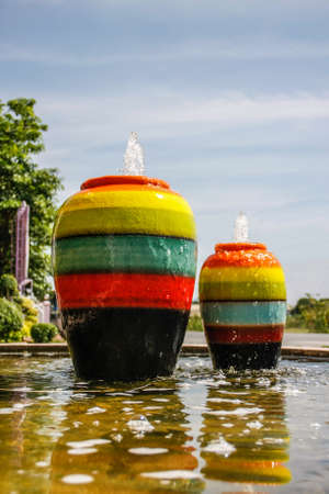 colorful jar pot fountain in pond front of entrance doorの写真素材