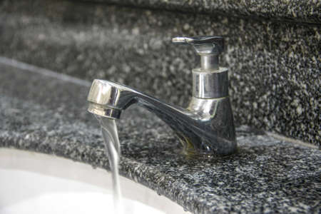 modern style faucet on granite tile with water drop in basinの写真素材