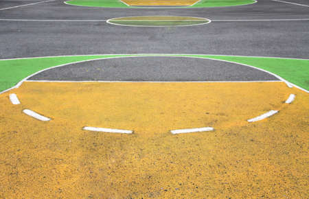 old playground outdoor basketball court made of asphalt and painted in yellow with greenの写真素材